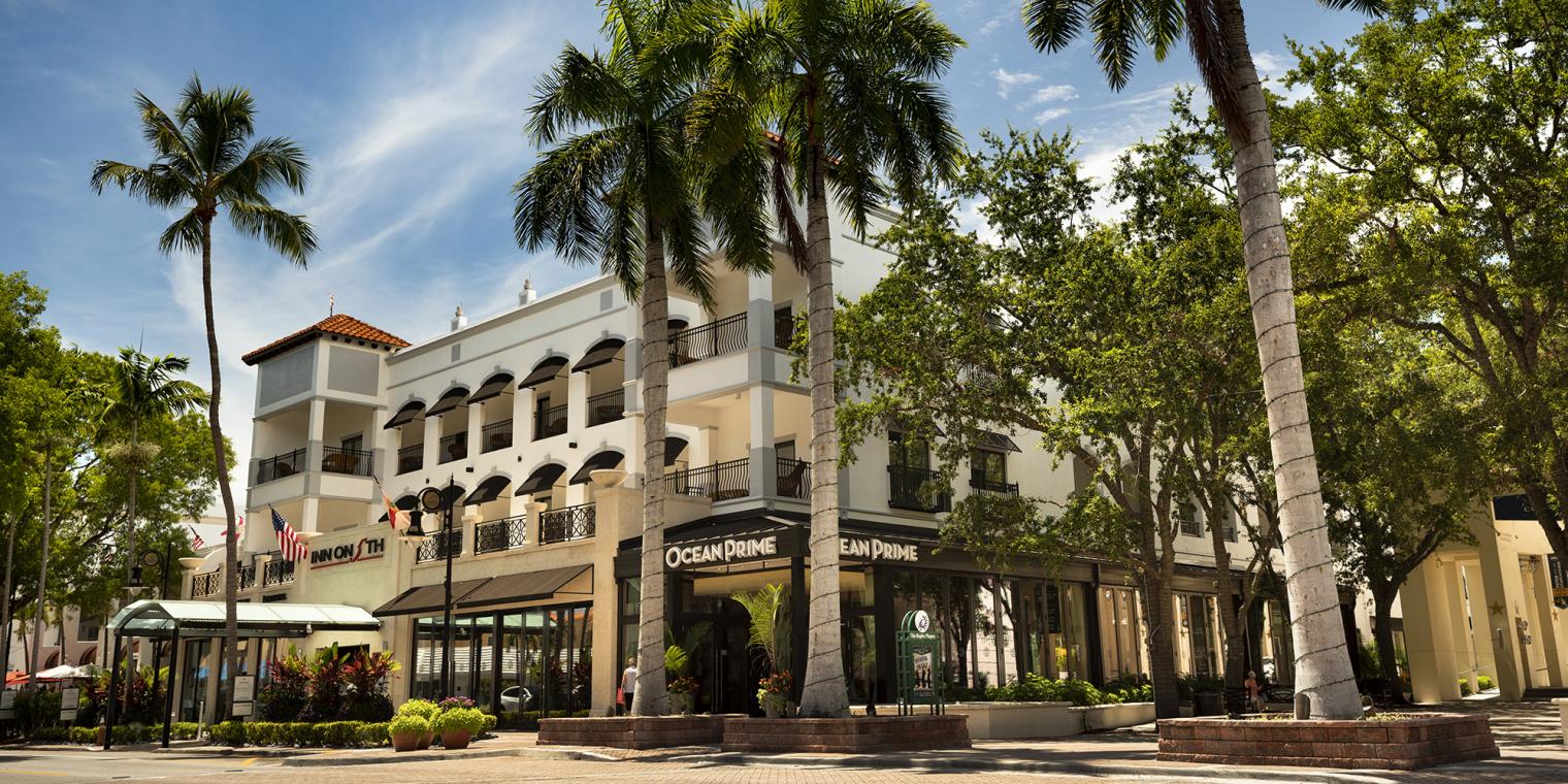 The exterior of Ocean Prime, a restaurant in Naples, surrounded by palm trees