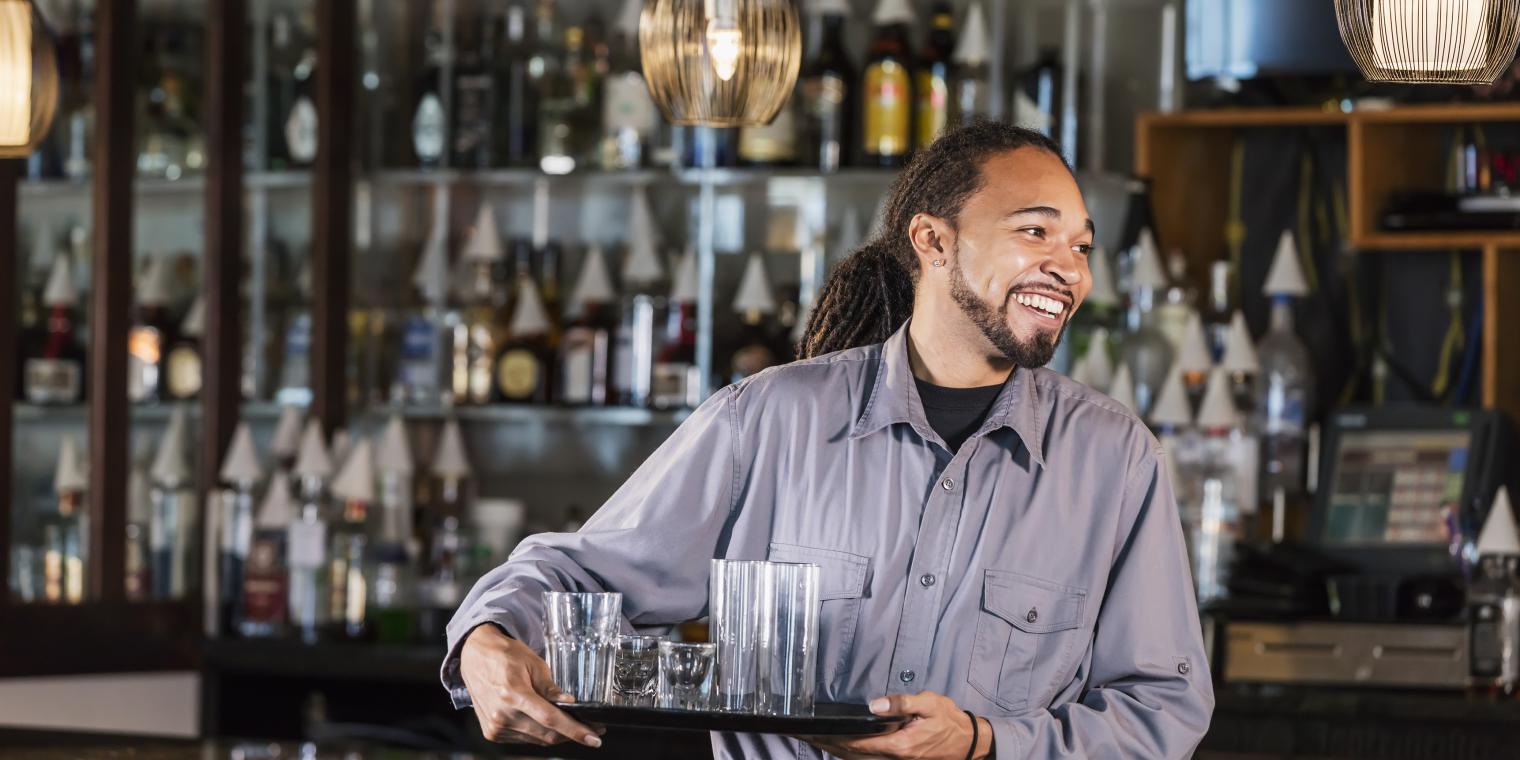 Bartender holding a tray of drinking glasses