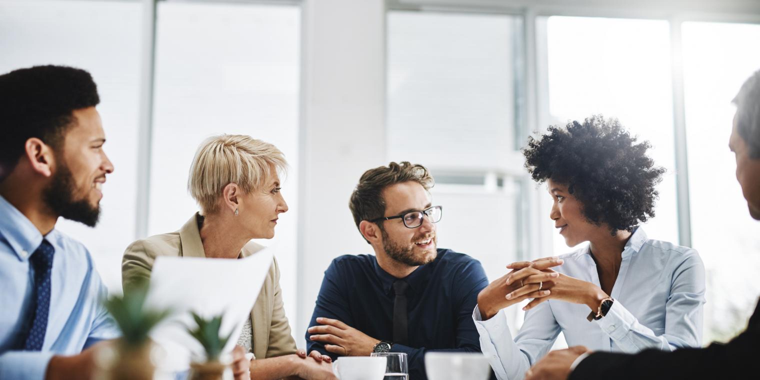 5 people having a meeting around a table