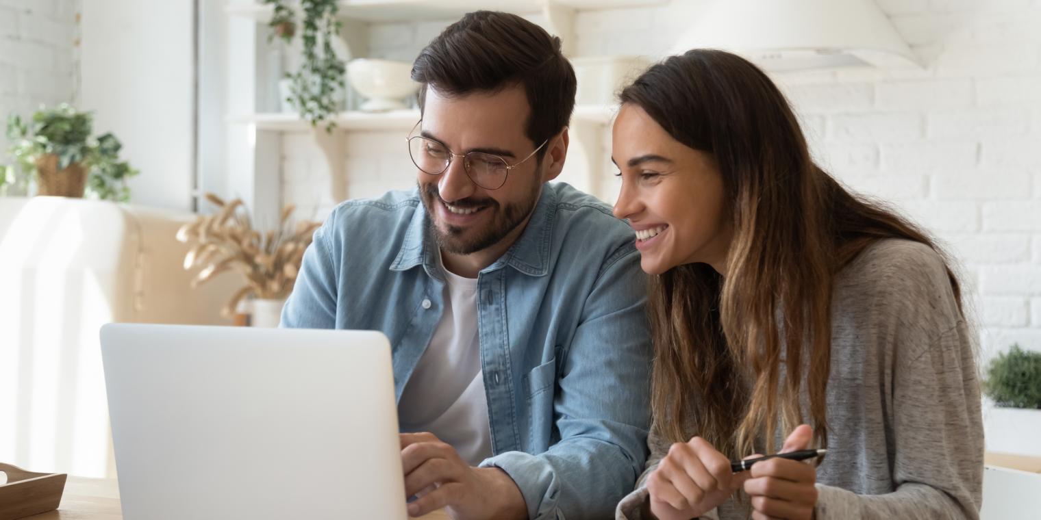2 people smiling looking at a laptop