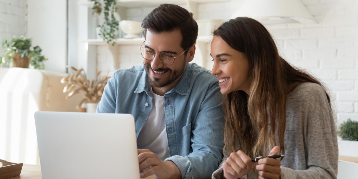 2 people smiling looking at a laptop 